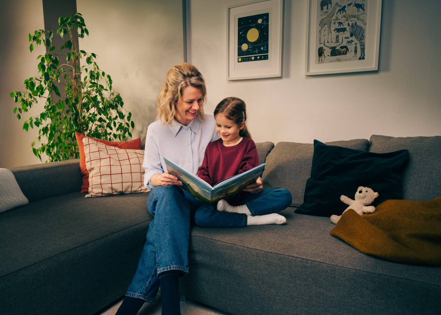 Mutter und Tochter sitzen auf der Couch und betrachten gemeinsam eine Volksbank Jugend Sparkarte.