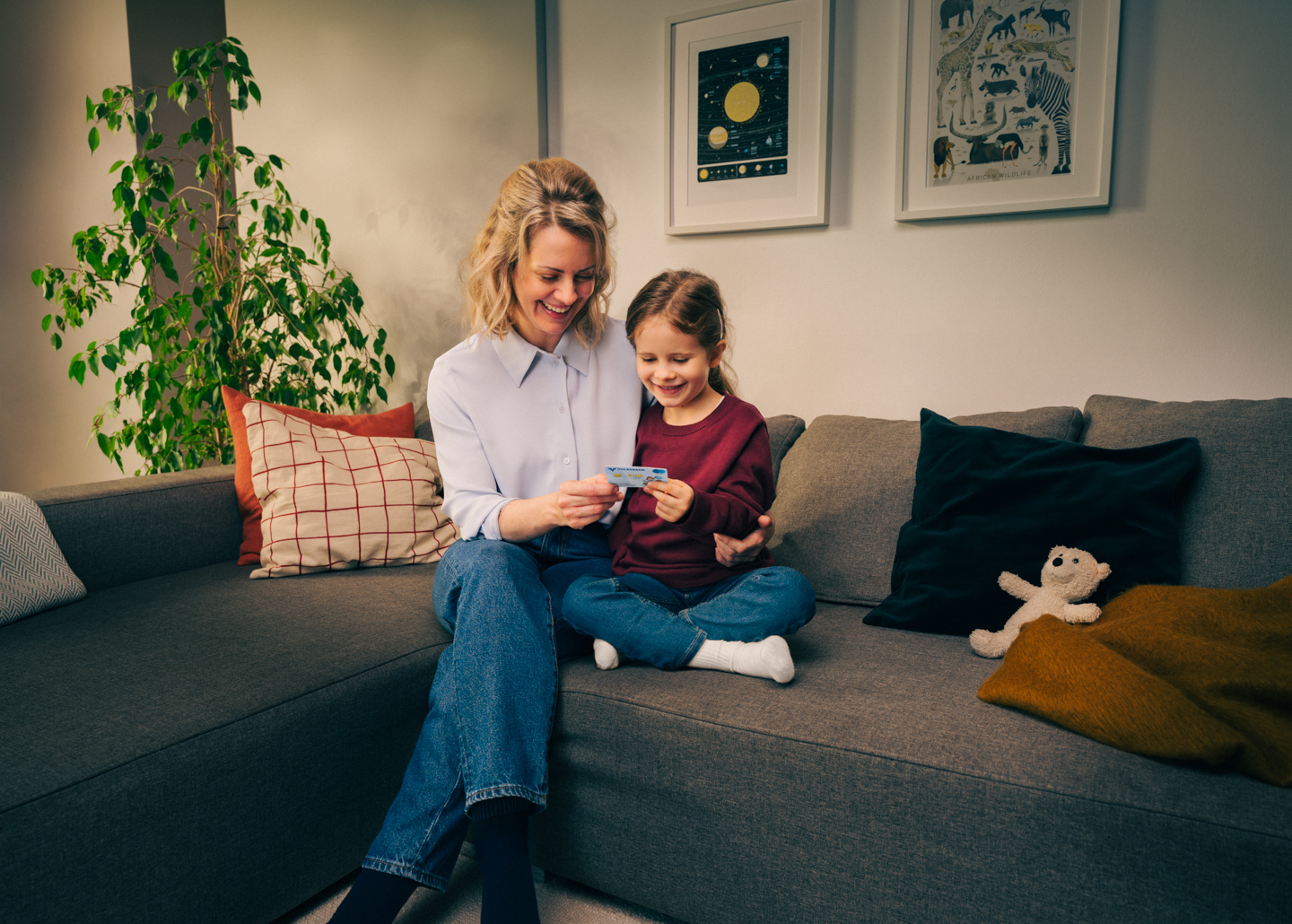 Eine Mutter sitzt mit ihrer Tochter auf der Couch und liest ein Buch.