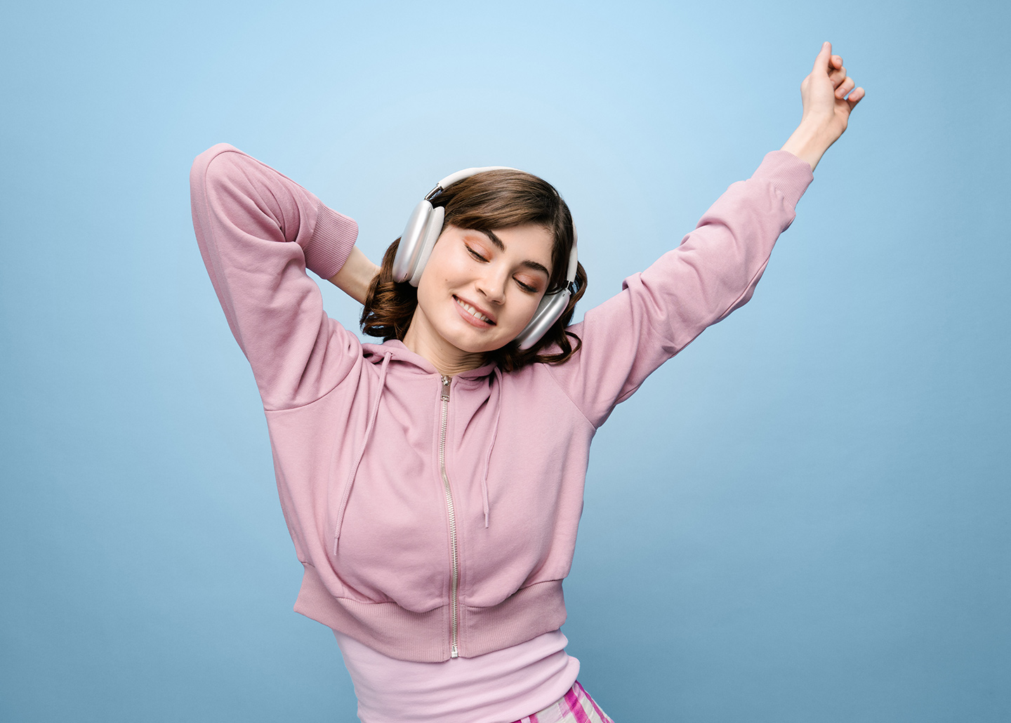 Eine junge Frau mit großen Kopfhörern tanzt zur Musik. Sie hat die Augen geschlossen.